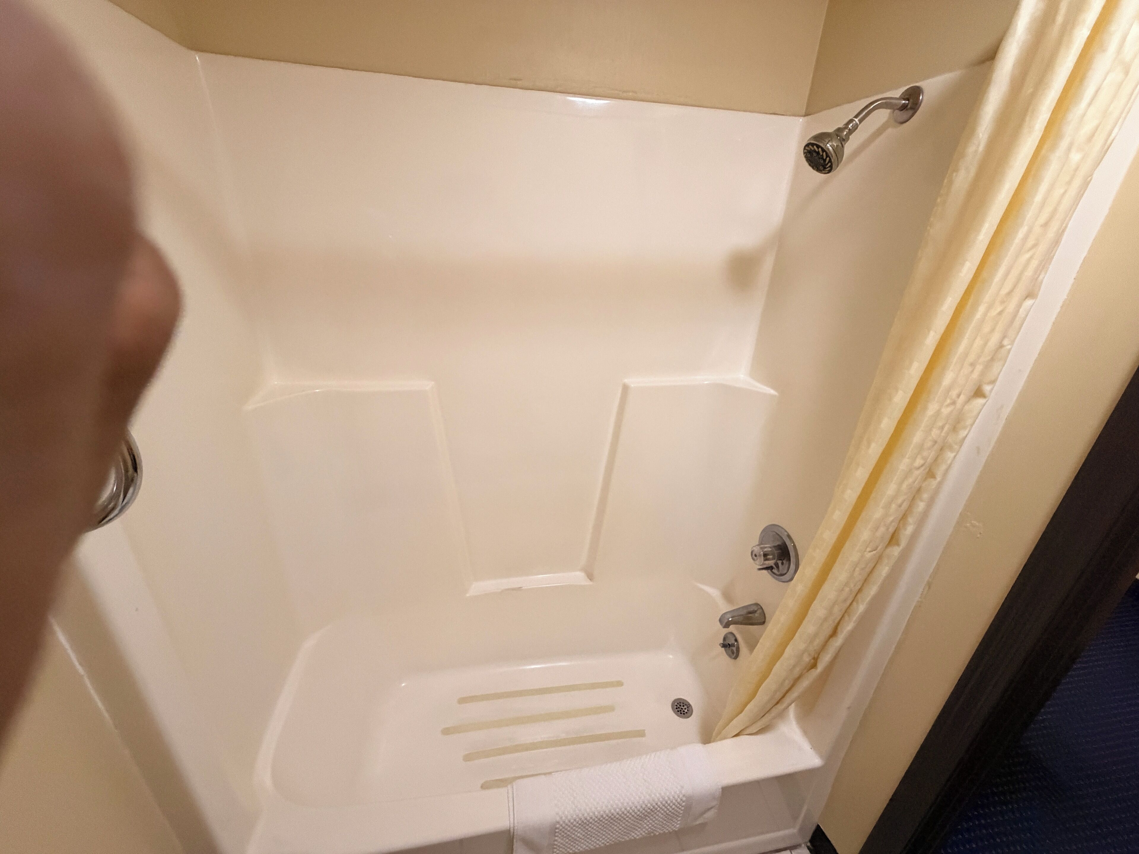 A bathtub with a showerhead, a towel rack, and a curtain.