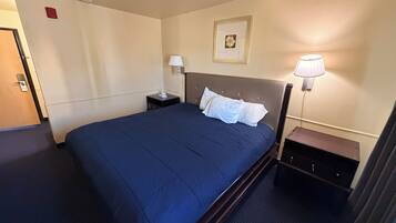 Habitación de hotel con una cama grande, mesitas de noche, lámpara de pared y un cuadro enmarcado.