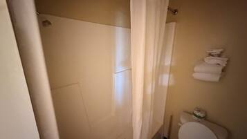 Un baño con ducha, inodoro y barra para toallas.