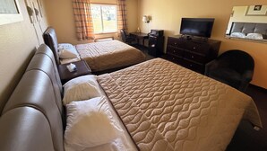 A hotel room with two beds, a desk, a chair, a television, and a window with curtains. - East Grand Inn Grand Forks ND I 29 (East Grand Forks)