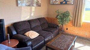 A living room with a dark brown sofa, a coffee table, a potted plant, and two abstract paintings on the wall. - East Grand Inn Grand Forks ND I 29 (East Grand Forks)