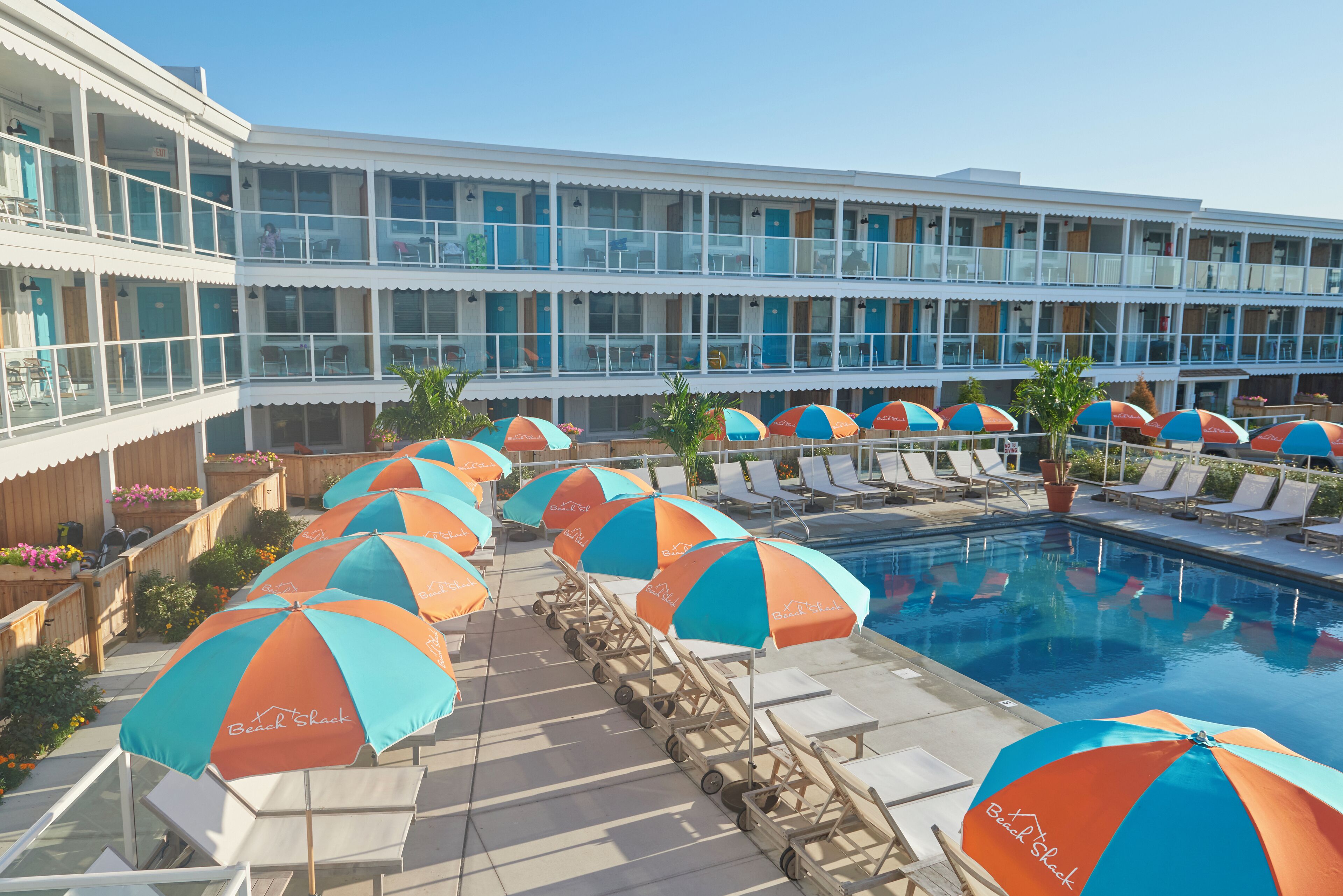 A hotel with a pool area featuring lounge chairs and umbrellas.