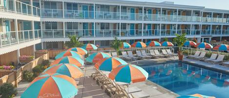 Un hôtel doté d’un espace piscine comprenant des chaises longues et des parasols.