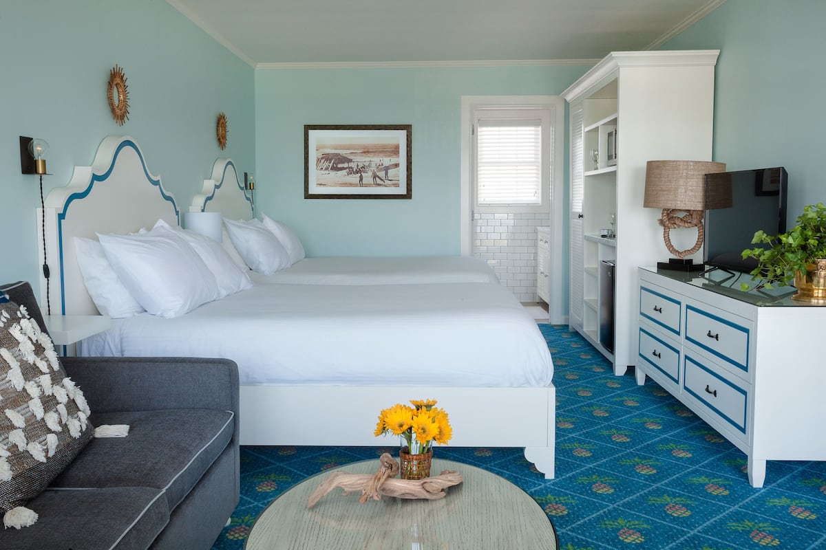 A bedroom with a bed, a sofa, a dresser, and a coffee table with flowers.