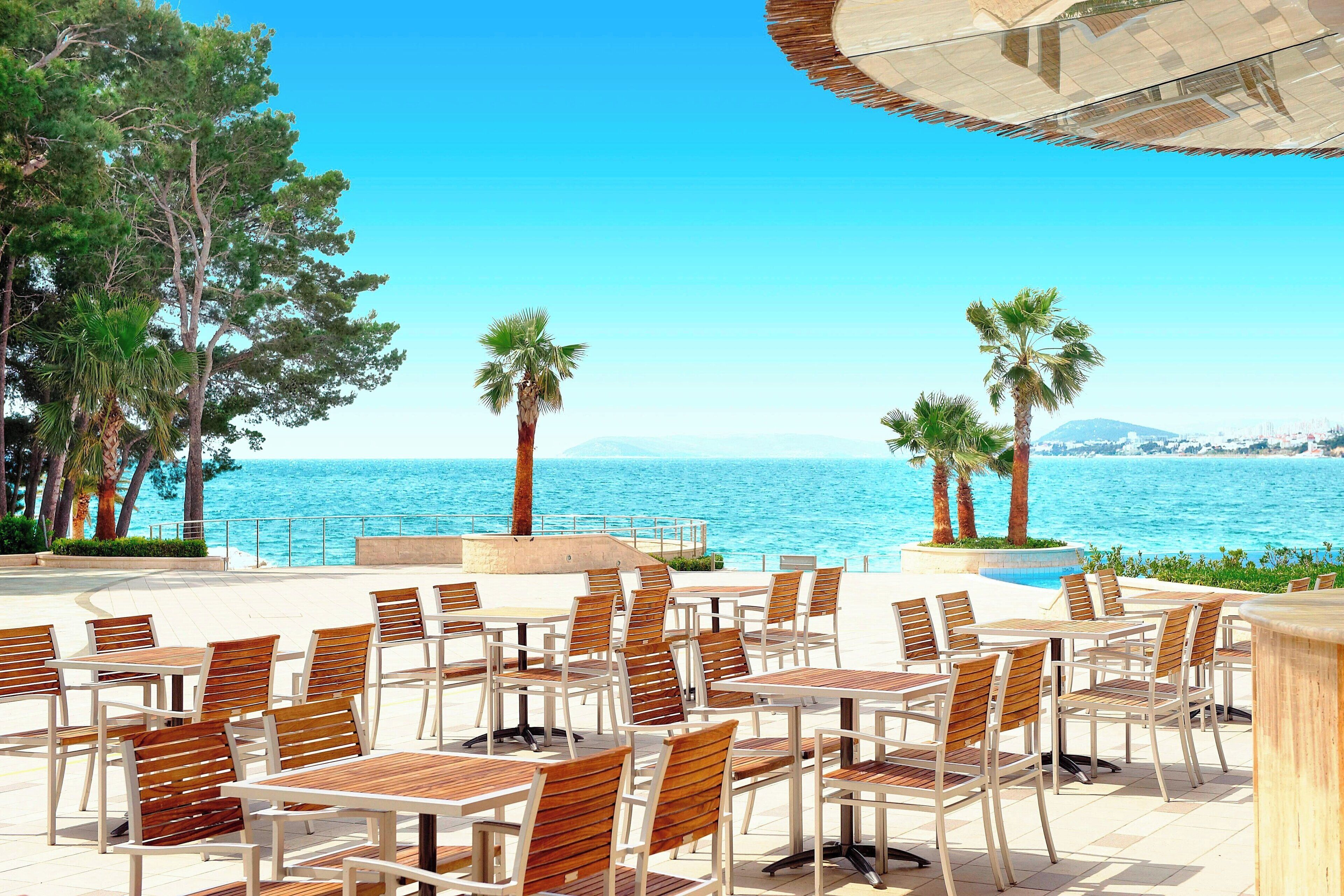 An outdoor seating area with tables and chairs, overlooking a body of water.