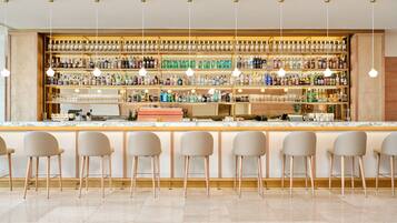 Een bar met meerdere flessenplanken, barstoelen en hangende吊り下げ型ライト.