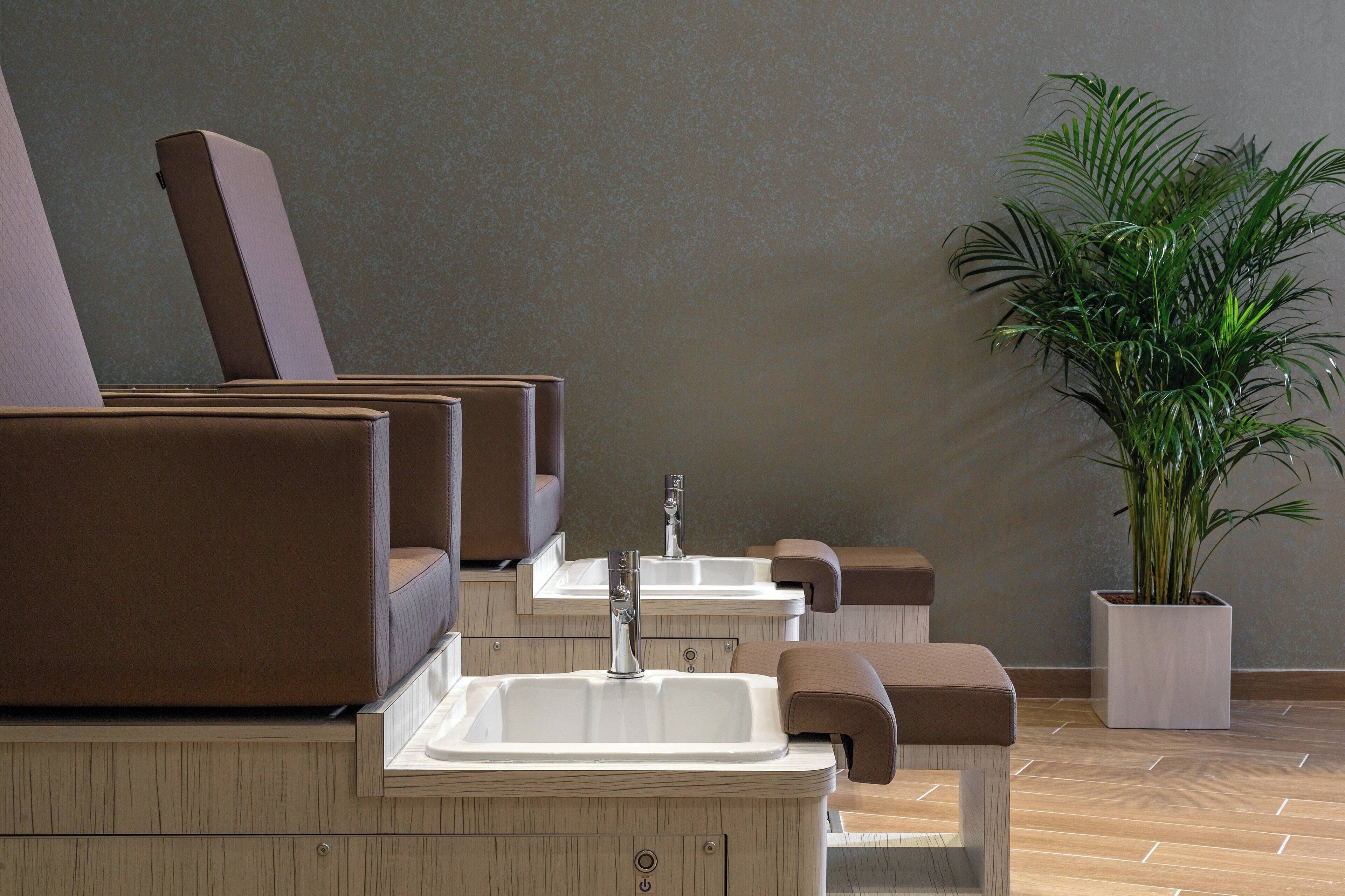 A modern bathroom with multiple sinks and cushioned seating areas.
