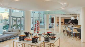 Amplia sala de estar moderna con bar, asientos y diversas mesas de exhibición de alimentos.