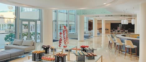 Amplia sala de estar moderna con bar, asientos y diversas mesas de exhibición de alimentos.