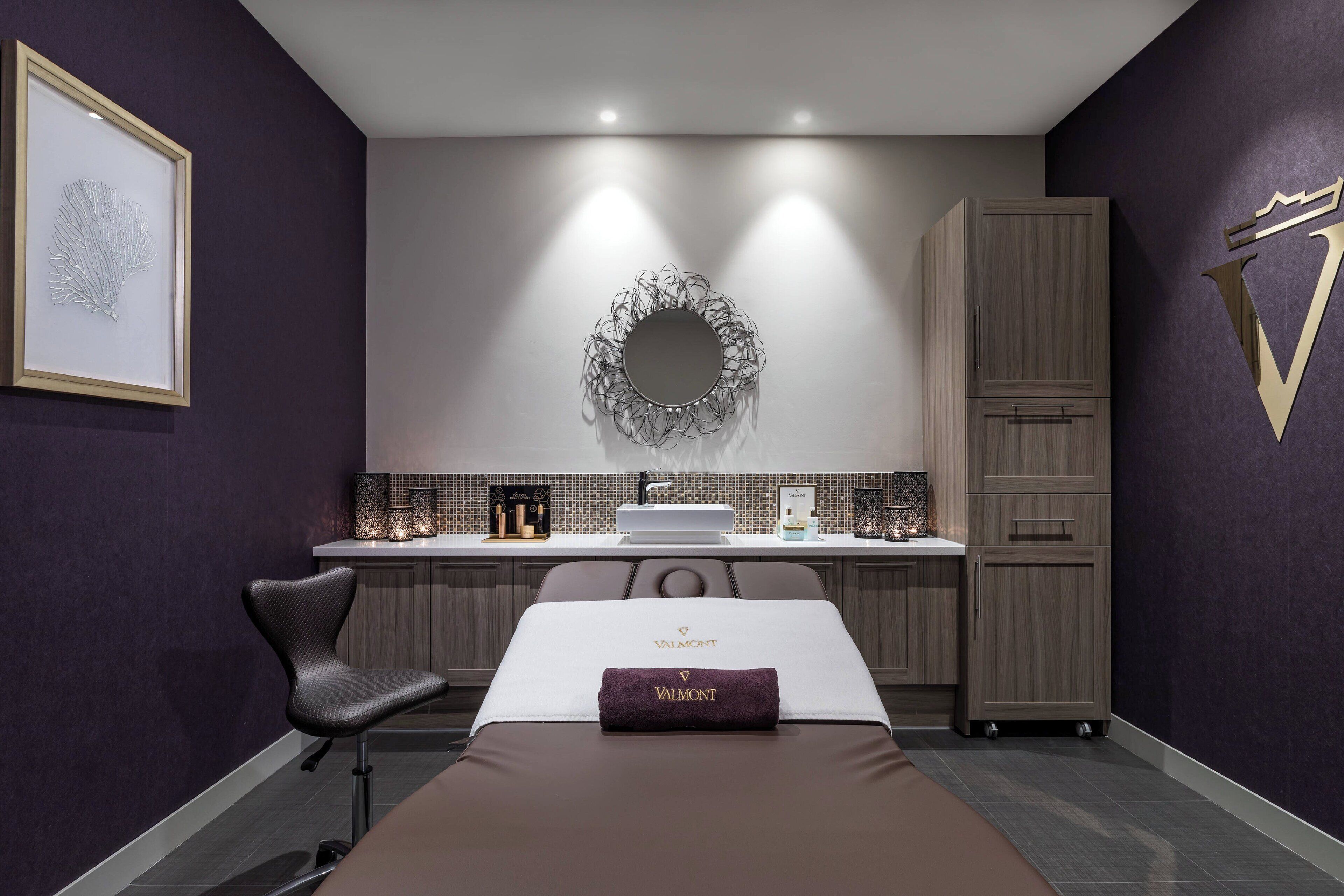 A modern hotel room with a bed, a seating area, a vanity with a mirror, and a wardrobe.
