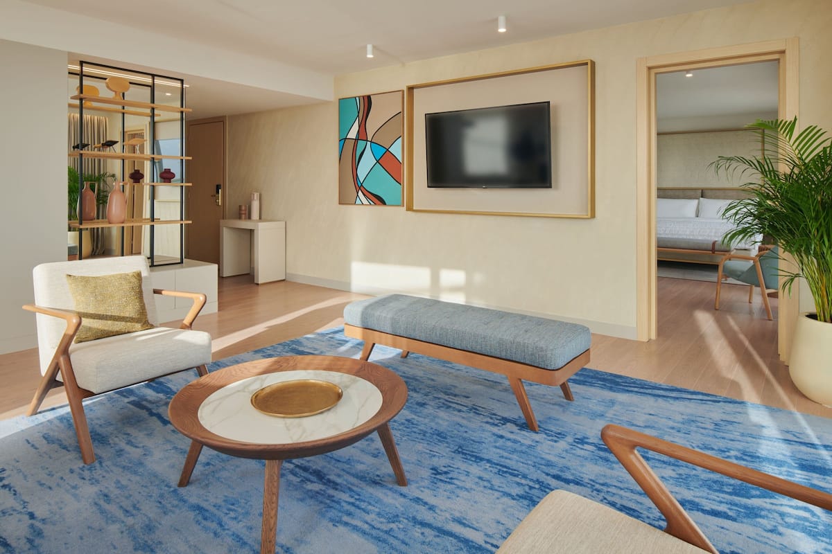 A modern living room with a sofa, a coffee table, and a TV mounted on the wall.