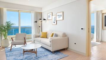 Una sala de estar moderna con un sofá, sillones, una mesa de centro y un ventanal con vistas al mar.