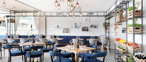 A restaurant with blue upholstered chairs, wooden tables, and a patterned floor.