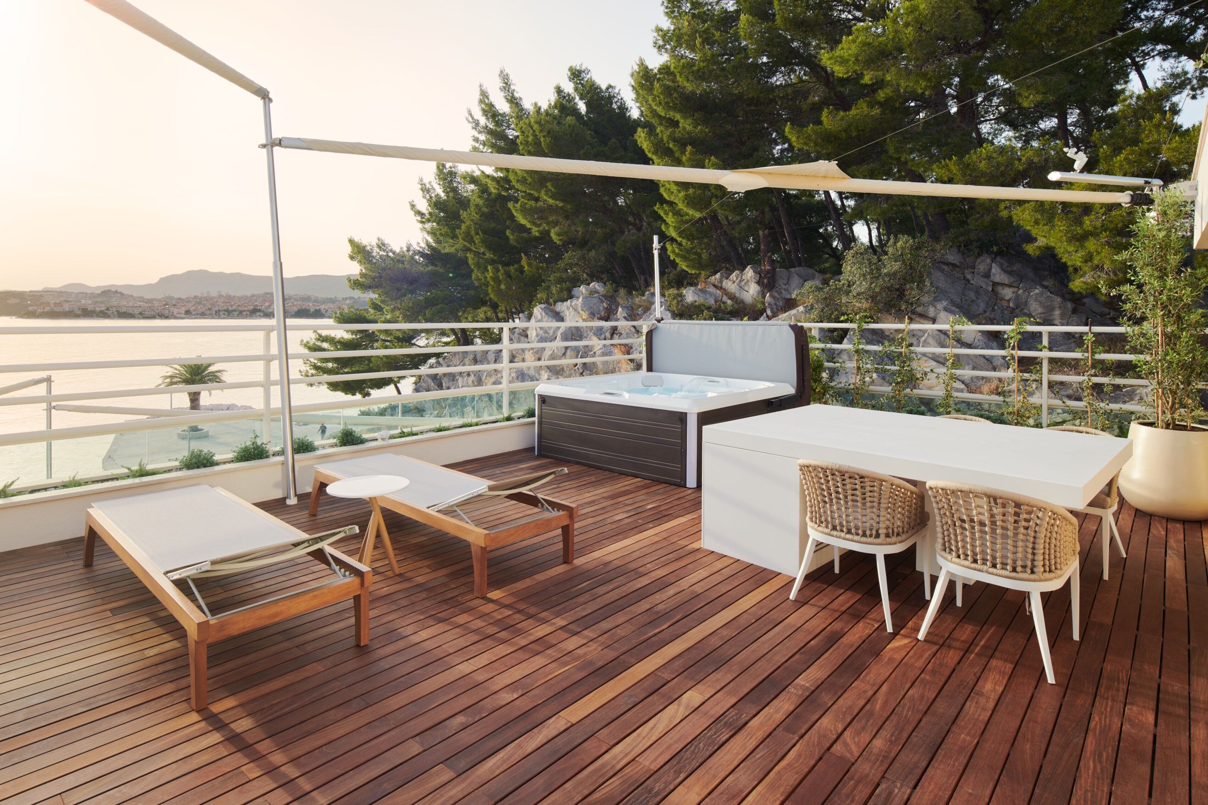 A wooden deck with a table and chairs, a sofa, and a hot tub.