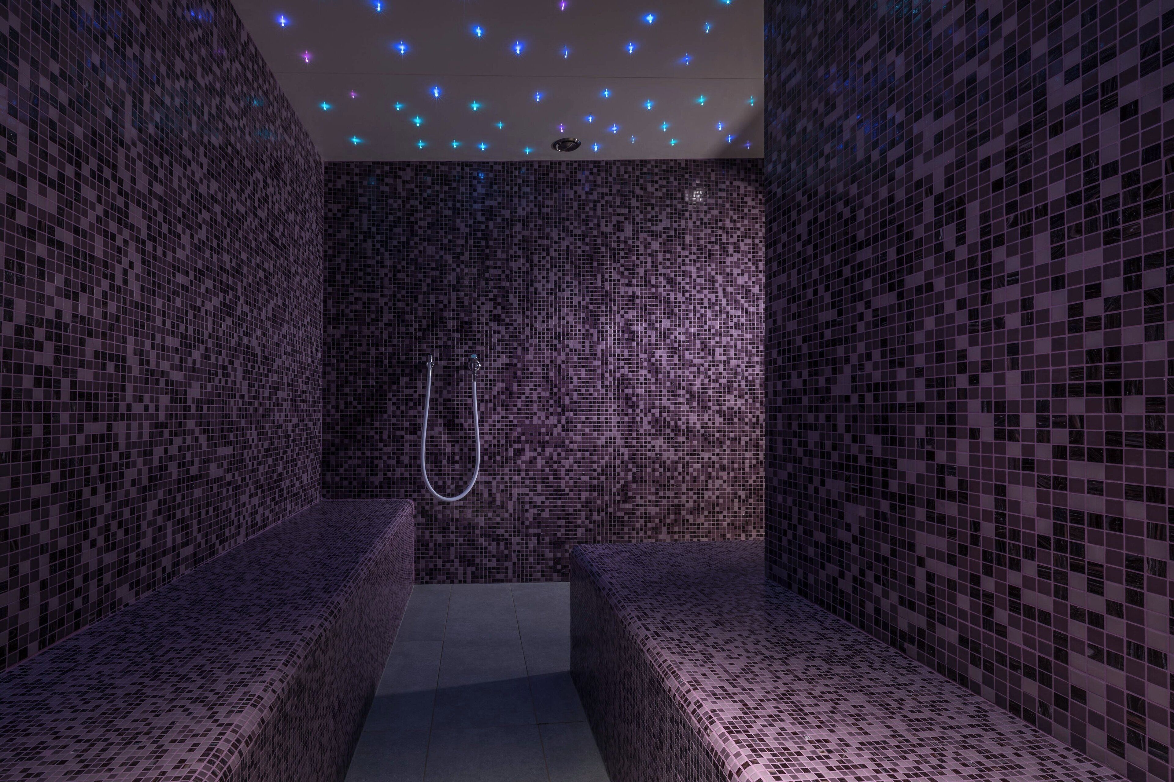 Une salle de spa aux murs et aux bancs recouverts de mosaïques.