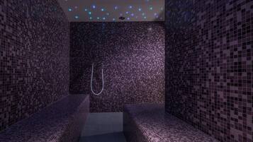 Ett spa-rum med väggar och bänkar som är beklädda med mosaik.