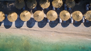 Vista aérea de una playa con hileras de sombrillas y un mar turquesa transparente.