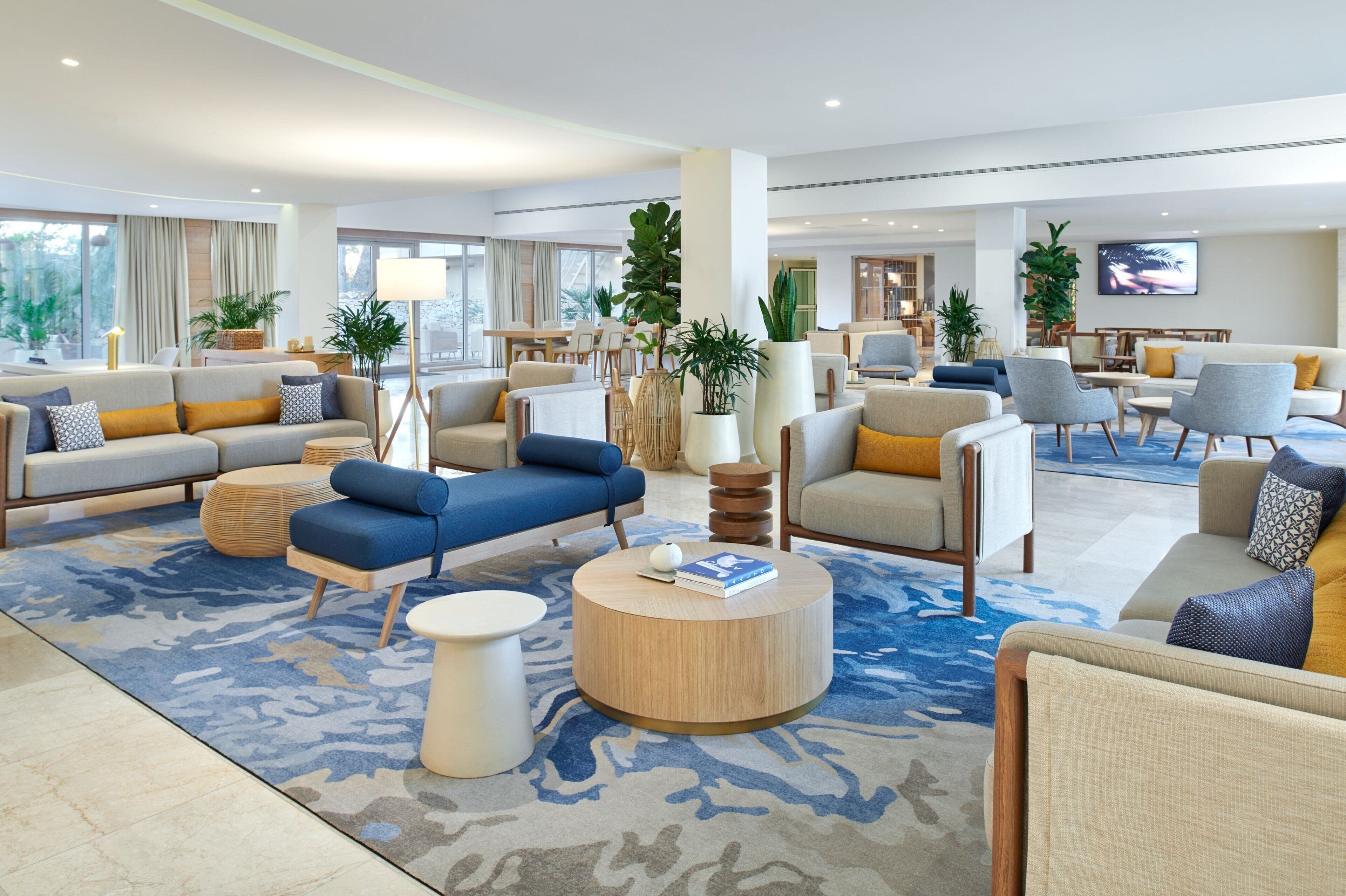 Amplia sala de estar con diversas opciones de asientos, incluyendo sofás y sillones, organizados alrededor de una mesa central.