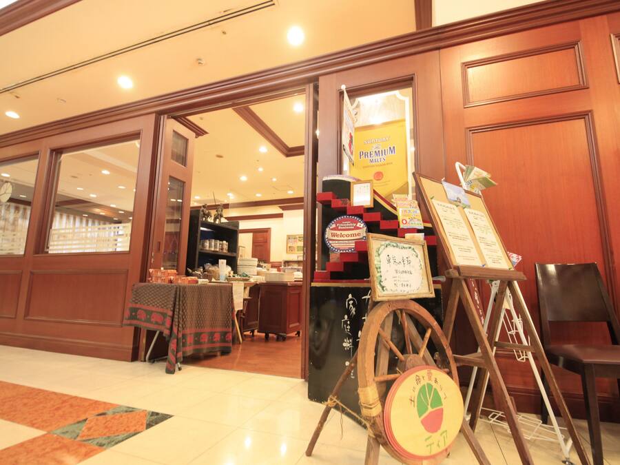 A hotel lobby with a reception desk, a wooden chair, and a signboard.