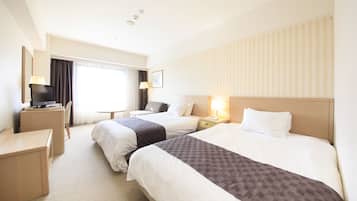 Een hotelkamer met twee bedden, een bureau, een stoel, een televisie en een raam met gordijnen.