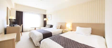 Een hotelkamer met twee bedden, een bureau, een stoel, een televisie en een raam met gordijnen.