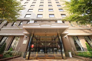 A hotel entrance with a glass door, a brick facade, and a sign reading "QUINTESSA".