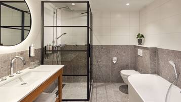 A modern bathroom with a glass shower enclosure, a freestanding bathtub, and a vanity with a mirror and sink.