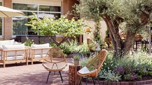 Eine Terrasse mit Korbstühlen, einem kleinen Tisch und einem Blumentopf.