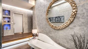 A modern lobby with a white sofa, a decorative mirror, and a framed artwork on the wall.