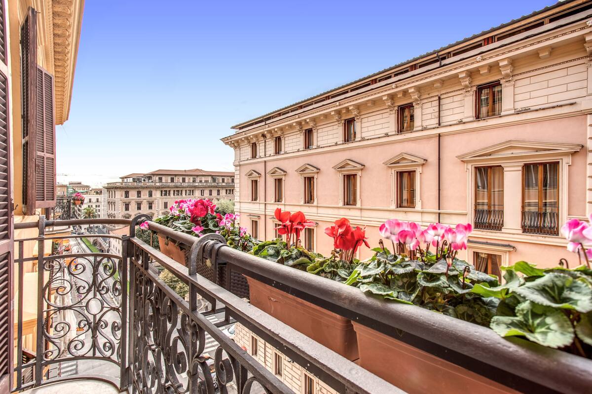 Un balcon orné de balustrades en fer forgé et de plantes en pot fleuries.