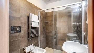 Ein modernes Badezimmer mit einer Duschkabine, einem Bidet und einem Waschbecken.
