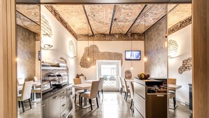 Eine moderne Küche mit Ziegeldecke, eine Essecke mit weißen Stühlen und einem Tisch sowie ein an der Wand montierter Fernseher.