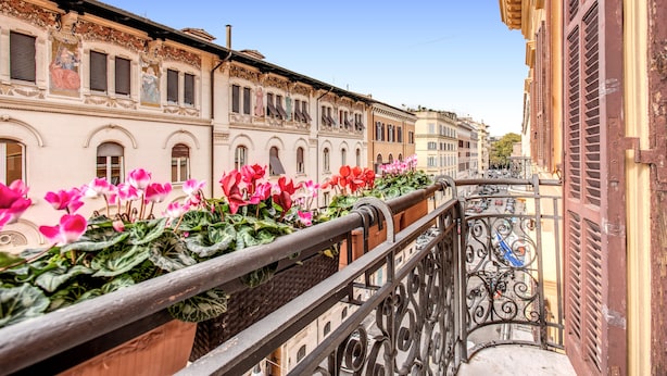 Ein Balkon mit schmiedeeisernen Geländern und Blumenkästen mit rosa und roten Blumen.