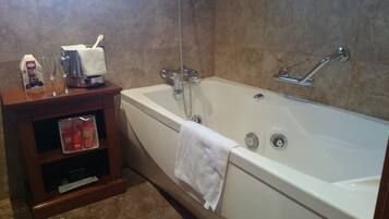 A bathroom with a bathtub, a shelf with toiletries, and a towel hanging on the wall.