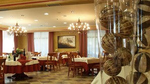 A dining area with tables set for service, a chandelier, and a large vase with decorative balls. - Villava Pamplona (Villava)