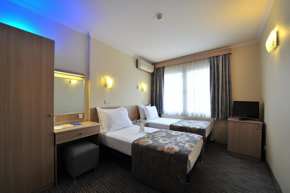 A hotel room with two beds, a desk, a television, and a wardrobe. - Hotel Olimpiyat (Istanbul)