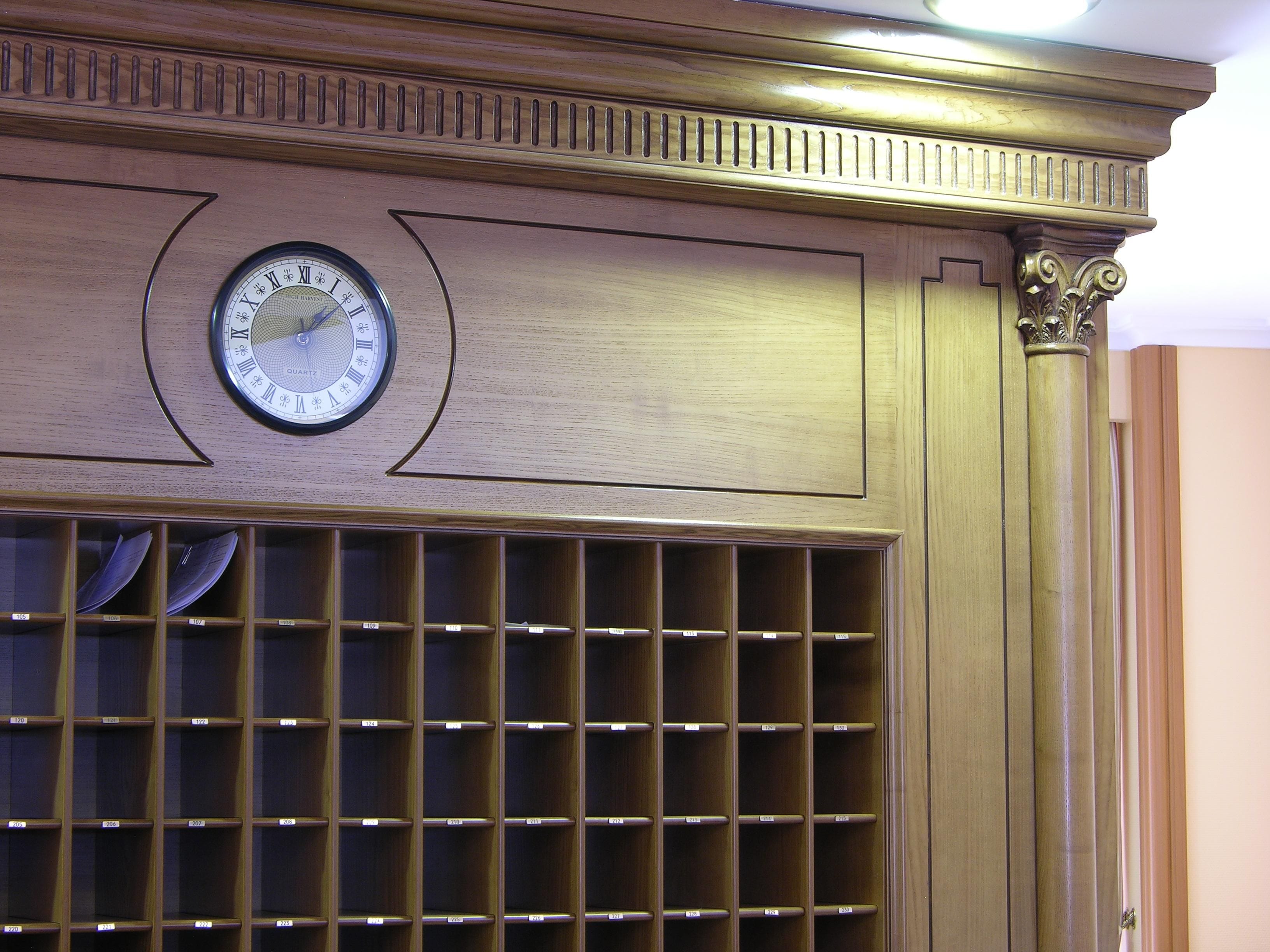 A wooden wall with a clock and a grid of shelves.