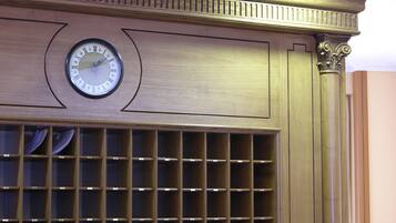 A wooden wall with a clock and a grid of shelves.