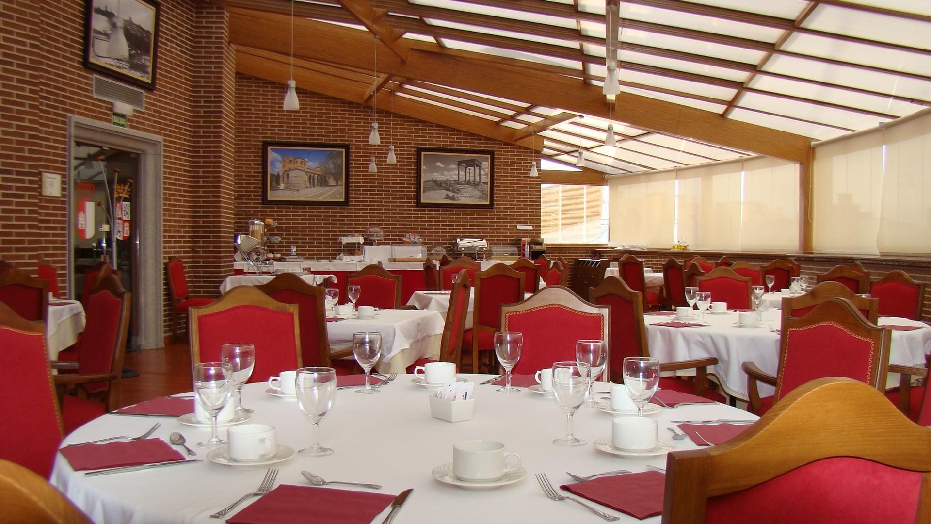 Un comedor con paredes de ladrillo, vigas de madera y mesas dispuestas para comer.