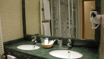 A bathroom with two sinks, a mirror, a towel rack, and a shower enclosure.
