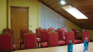 A conference room with a long table, red upholstered chairs, a wooden ceiling, and a window with blinds.