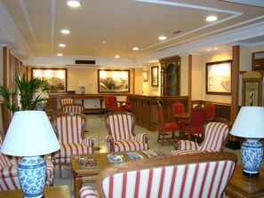Un vestíbulo de hotel con sillas a rayas, un mostrador de recepción y obras de arte enmarcadas en las paredes.