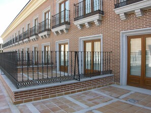 A multi-story brick building with a balcony, a door, and a window.