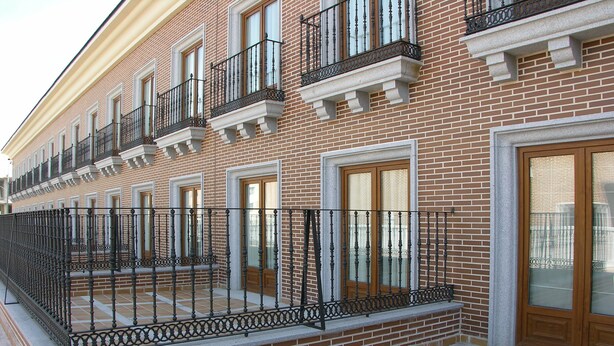 A brick building with multiple windows and balconies. - Dos Castillas (Ávila)