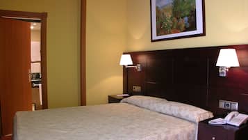 A hotel room with a bed, two bedside lamps, a nightstand with a phone, and a painting on the wall.