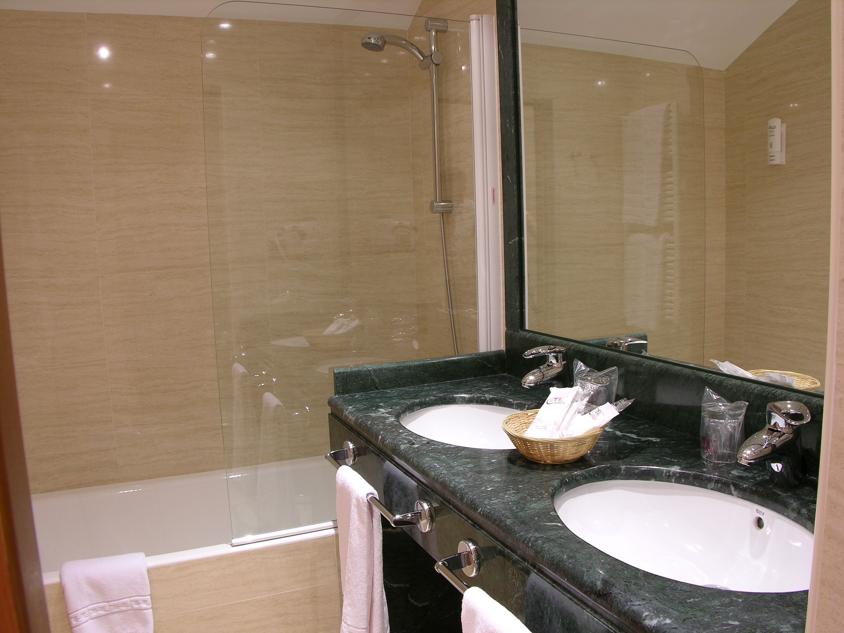 Un baño con dos lavamanos, una ducha y un espejo grande.