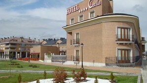 A hotel named 'HOTEL Castillas' with a curved brick facade, multiple windows, and a balcony. - Dos Castillas (Ávila)
