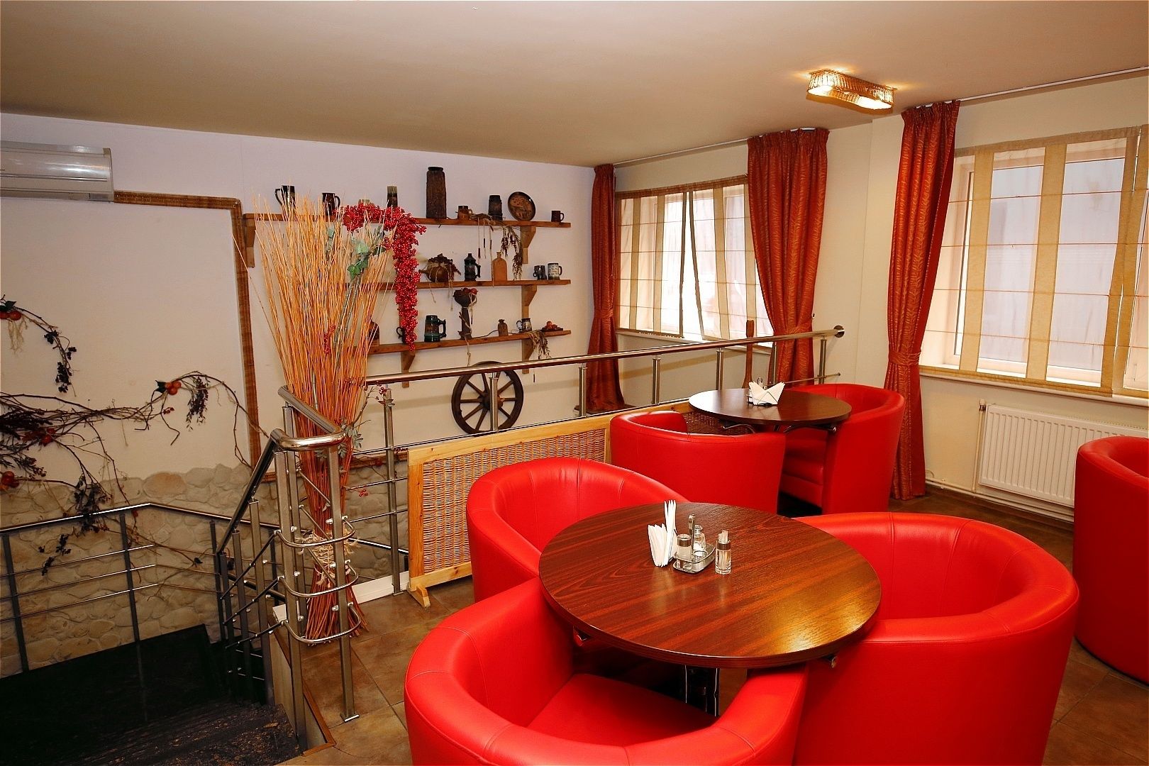 Una habitación con sillas de cuero rojo, una mesa de madera y una pared decorada con diversos objetos, incluyendo una rueda de carruaje.