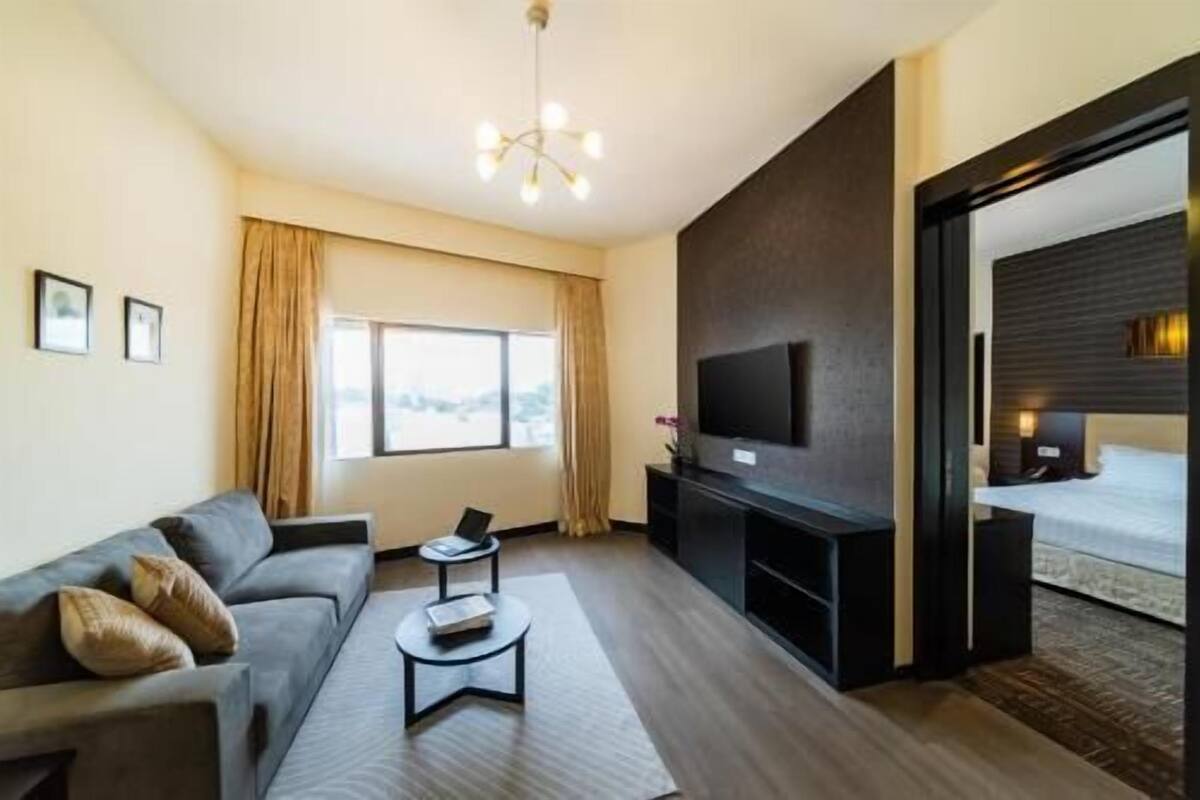 Une chambre d’hôtel moderne équipée d’un canapé, d’une table basse, d’un téléviseur à écran plat et d’une grande fenêtre.