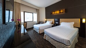 Een hotelkamer met twee bedden, een bureau, een stoel, een groot raam en een modern wandontwerp.
